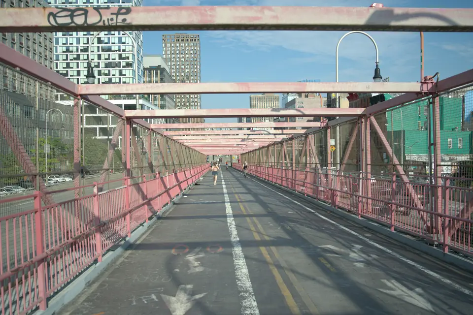 The pink steel bike and pedestrian path of the Williamsburg Bridge looking toward Manhattan