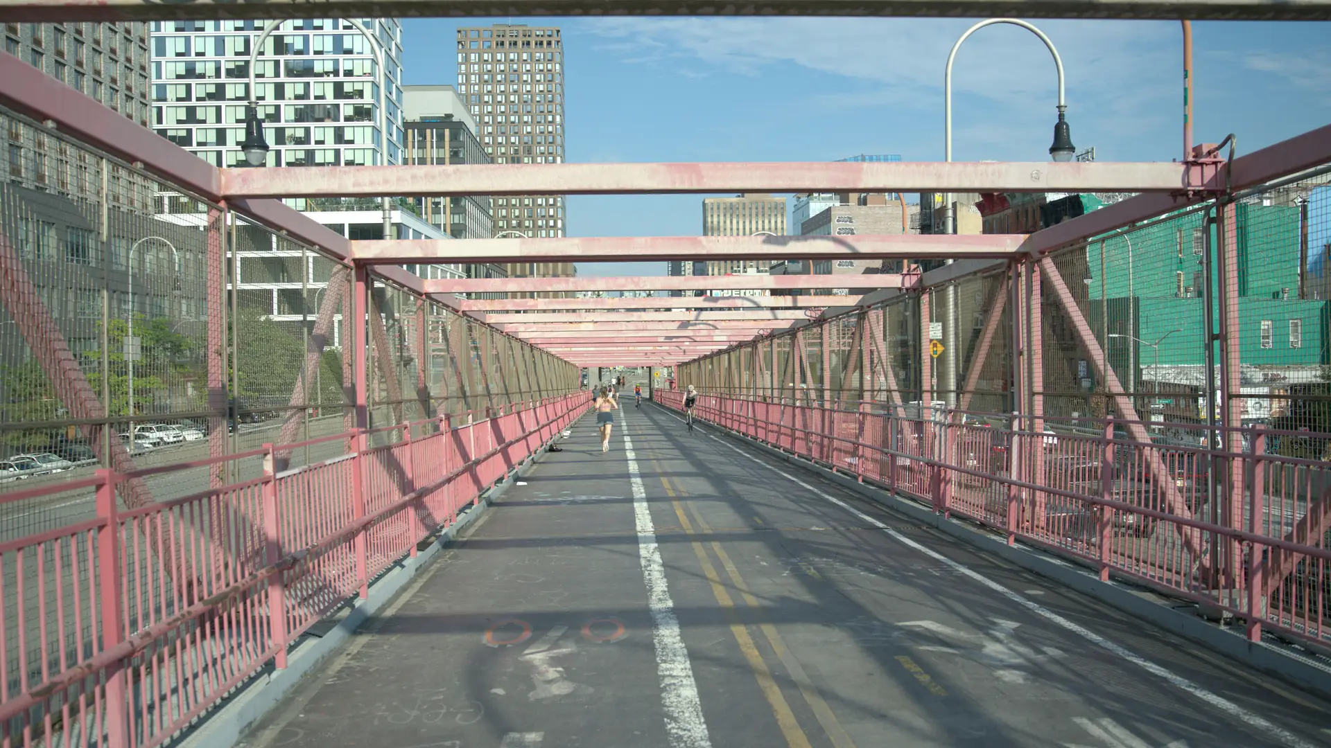 The pink steel bike and pedestrian path of the Williamsburg Bridge looking toward Manhattan